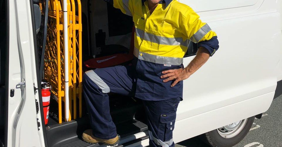 Australian tradie in hi-vis with work van